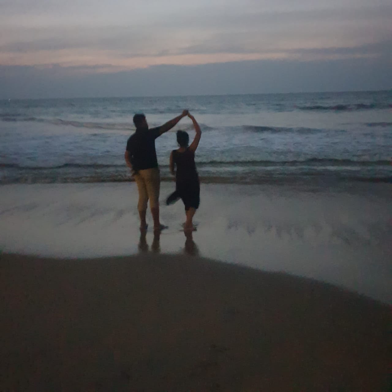 Amanda and Ashwinth dancing on the beach at dusk